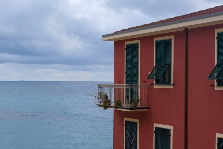 Fachada Vermelha Do Edificio Com Vista Para O Oceano Sob O Ceu Nublado qGjmzZ7aKGM