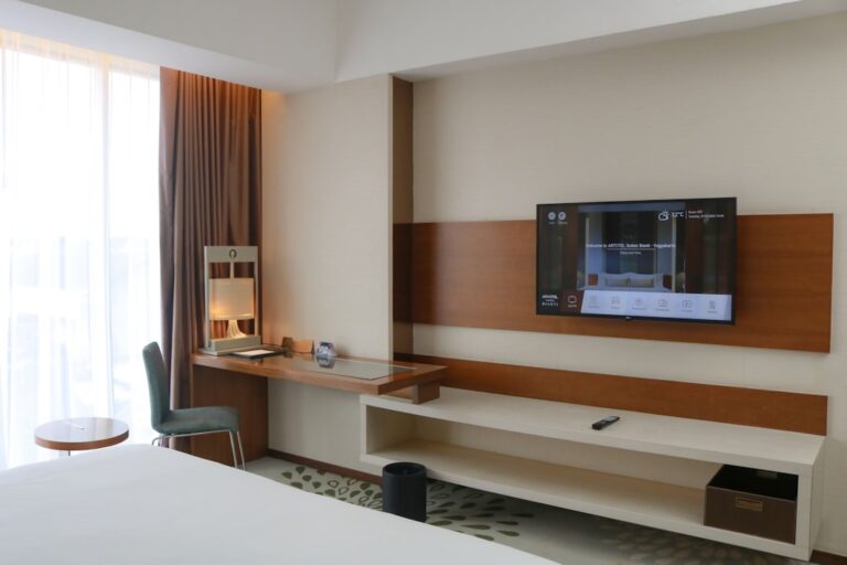 Um Quarto De Hotel Com Uma Tv De Tela Plana Na Parede BvMcKKh0O E