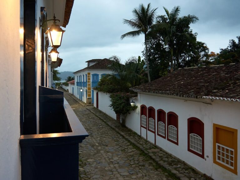 Edificio De Concreto Branco E Vermelho Perto Da Palmeira Verde Durante O Dia VRDc8Q1kwPY