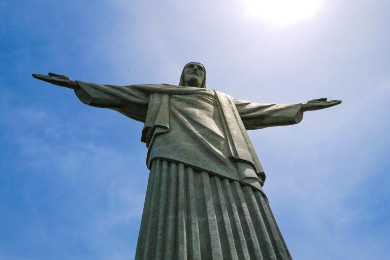 Low-angle view of the Christ the Redeemer statue in Rio de Janeiro against a vibrant blue sky.