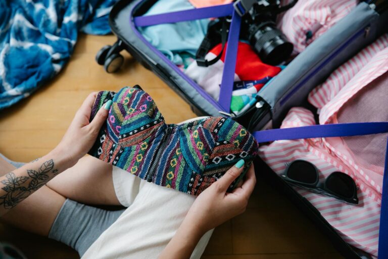 A woman packing a colorful bikini into a suitcase, preparing for her vacation trip.