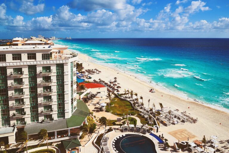 Aerial view of a luxurious beachfront resort in Cancún, showcasing a pristine coastline with turquoise waters.