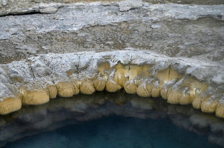 Close-up of a natural rock formation surrounding a geothermal pool with unique textures.