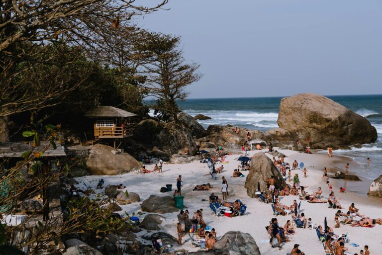 Lively beach in Rio de Janeiro with people enjoying the sun by the rocky shoreline.