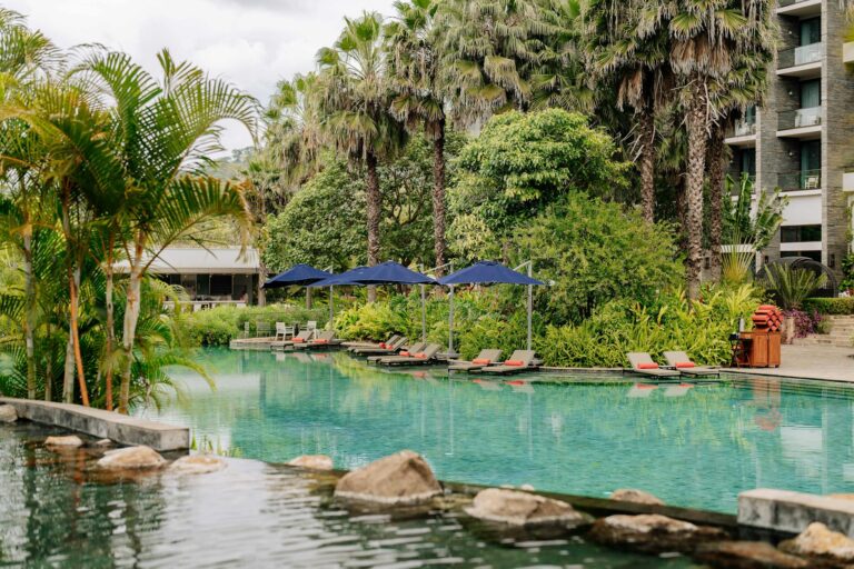 Relaxing view of a tranquil outdoor pool surrounded by lush greenery at a resort in Arusha, Tanzania.