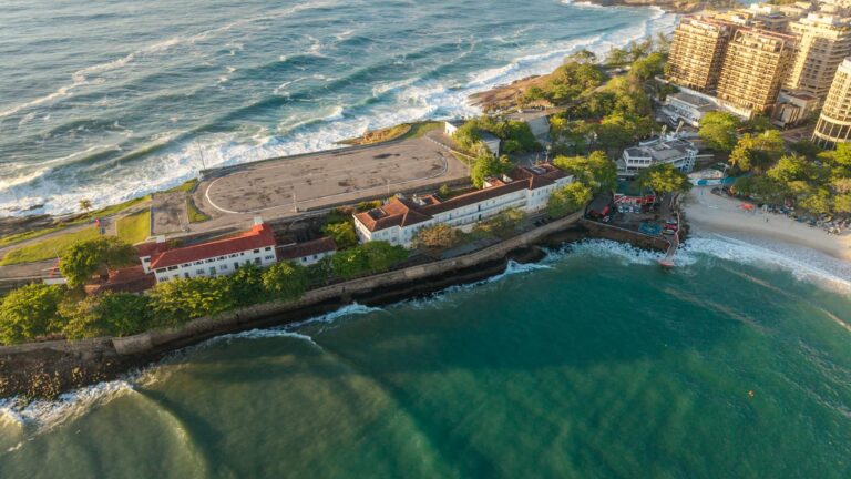 Scenic aerial view of the coastline in Rio de Janeiro, Brazil, with golden sunlight reflecting off the waves.