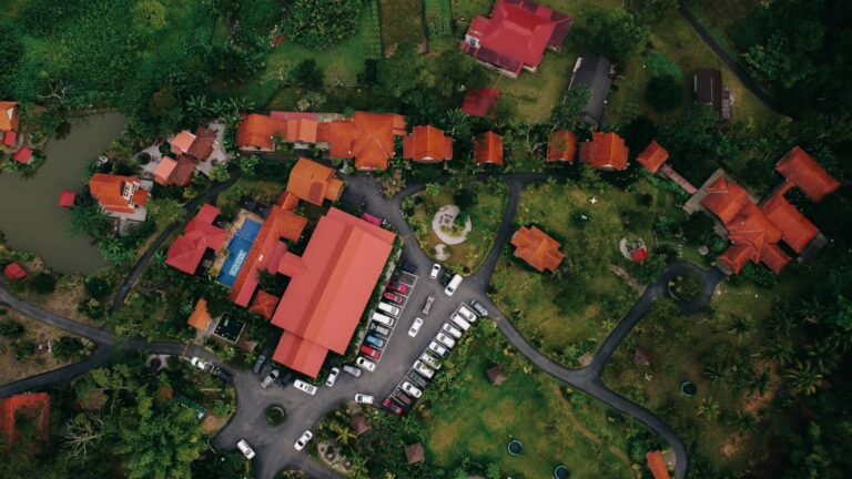 Aerial shot of a lush residential compound with distinctive red rooftops and a parking area.